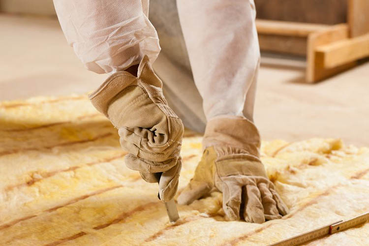 how to weatherize your home, close-up photo of hands cutting insulation