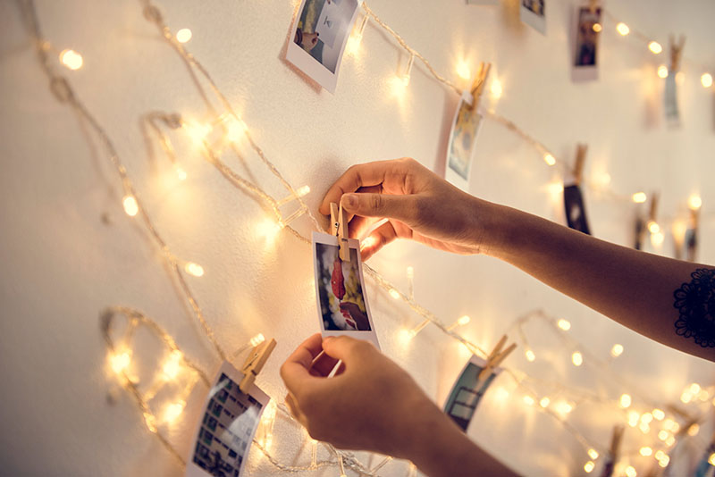 Closeup of hands with photos hanging with decoration lights on t