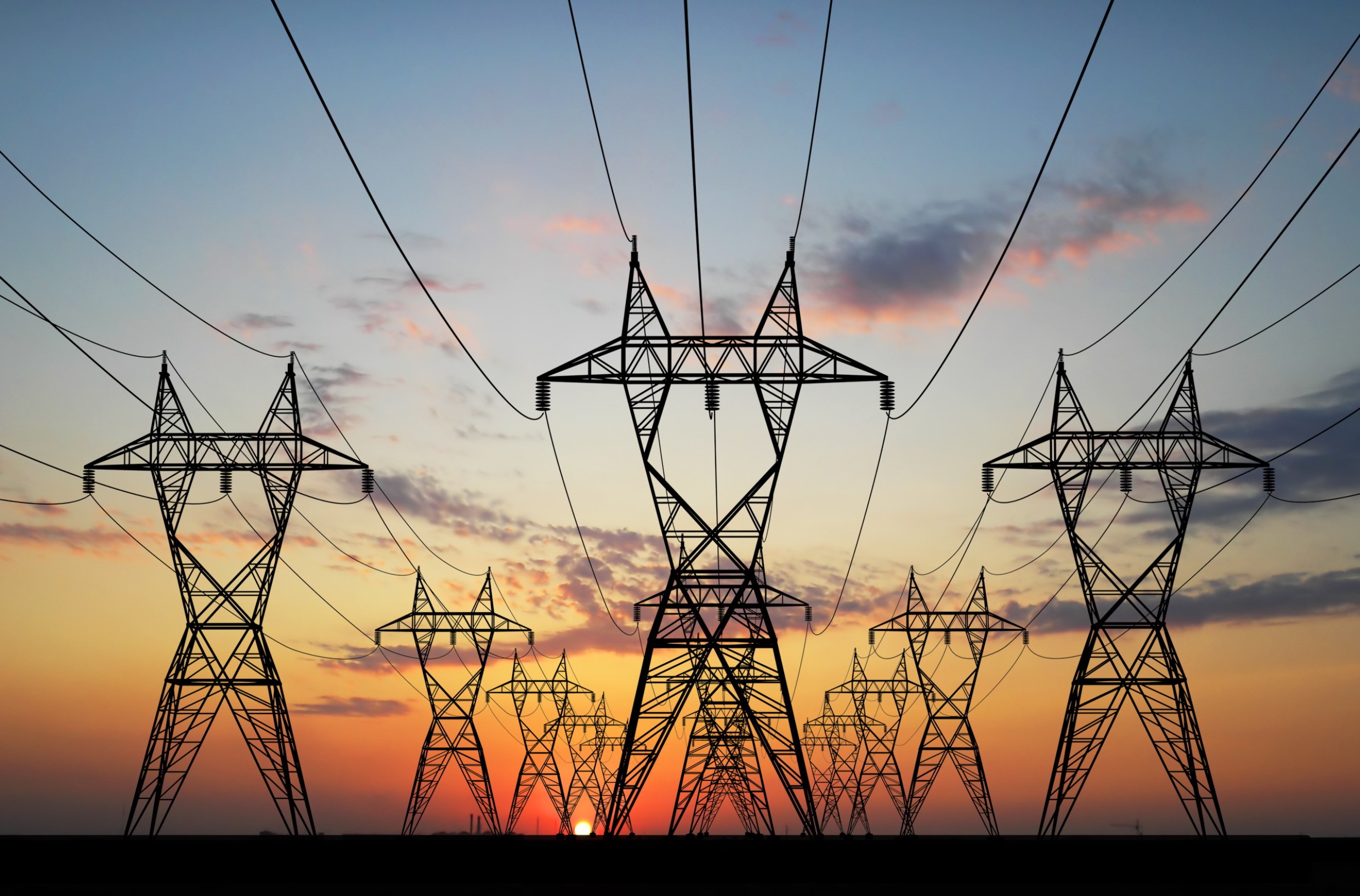 transmission lines silhouetted against a sunset demand for power