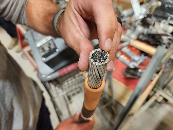 Tyler Vaughan holds a piece of cable, showing the end of the section. 