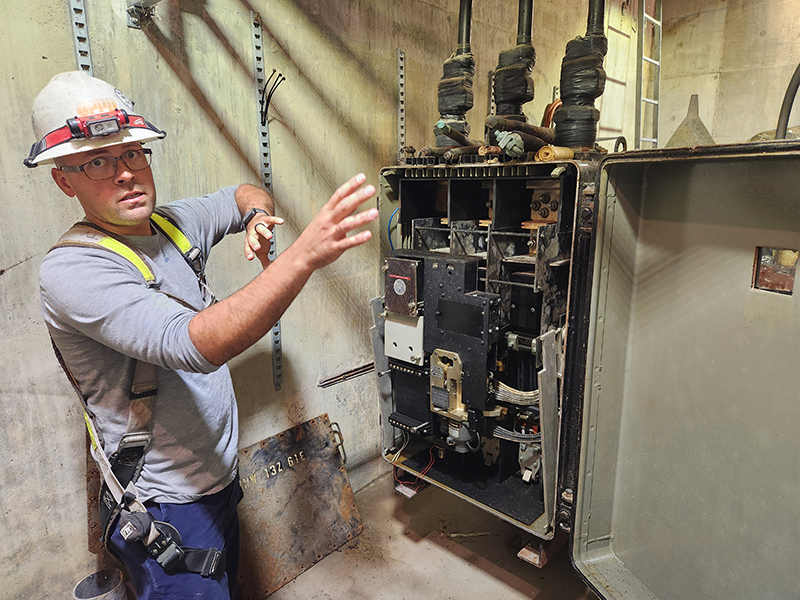 Tyler Vaughn, a cable splicer at OPPD, stands in front of an underground switching device.