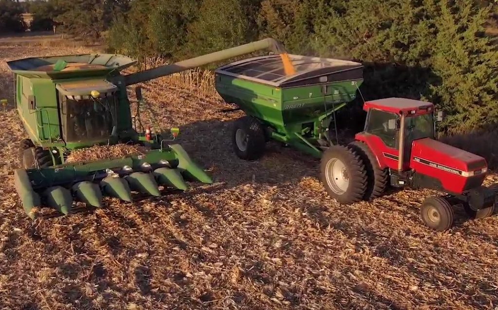 A farmer transfers corn from his combine to a grain trailer, which is attached to a tractor. Following safety tips can is a vital part of a successful harvest.