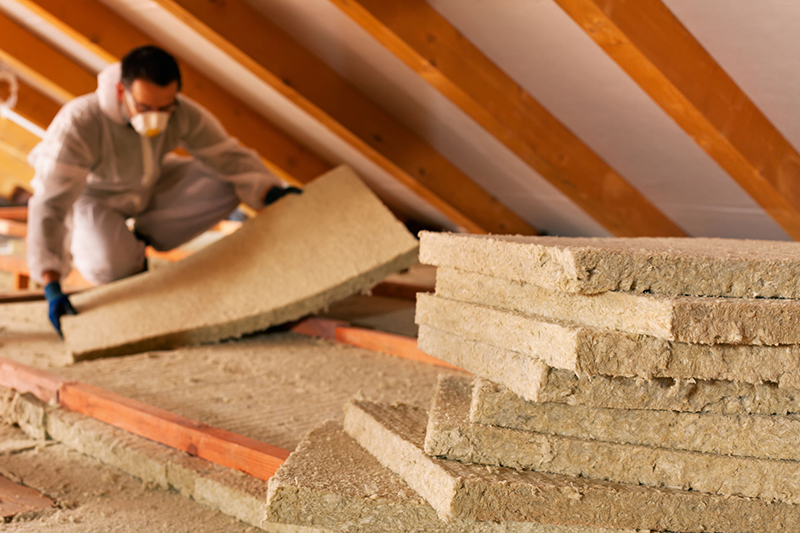 A man installs insulation in the attic of a home. OPPD's Energy Efficiency Assistance Program helps qualifying customers make weatherization updates to their homes.