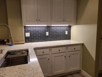 Shane Hanson relaxes doing home improvement projects. Show here is the bar area he built in his house, with white cabinets and a sink.
