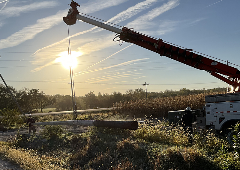 OPPD workers stand in a field along the road, preparing to install distribution lines.