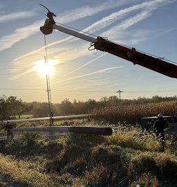 OPPD workers stand in a field along the road, preparing to install distribution lines.