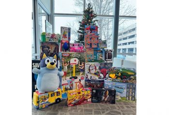 Some of the toys collected for Toys for Tots sit in front of a Christmas tree. The toy drive is one of the many ways employees spend time giving back for the holidays.