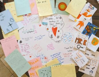 Thank you notes from students are spread on a table top.