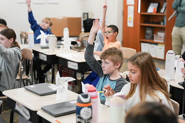 Students raise their hands during a visit from Eric BenSalah as part of OPPD's Energy Education Program. 