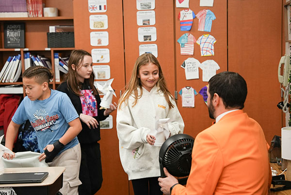 Energy Consultant Eric BenSalah, the master of OPPD’s Energy Education Program, points a fan at a student's paper pinwheel to test whether the pinwheel blades will spin.