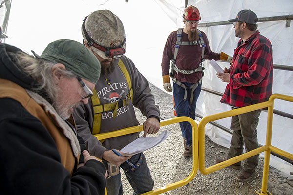 Mark Doeppers and Curtis Vlasak look through papers with applicant rankings while Tyler Holmes and Eric Devney talk nearby.