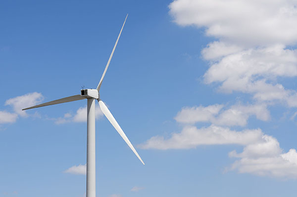 A wind turbine is shown against a light blue sky.