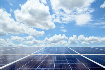 Clouds and sunlight reflect off of solar panels.