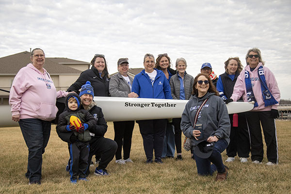 Bridget Navratil stands with other members of Stronger Together, holding a boat with the group's name printed on it.