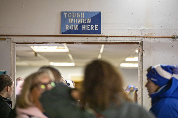 A sign that hangs above a doorway reads "Tough women row here."