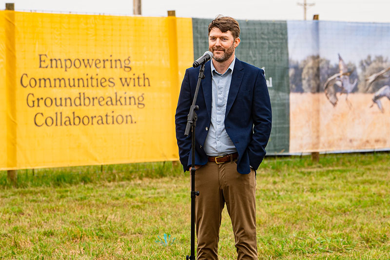 Sandhills Energy President Eric Johnson in front of a banner at a groundbreaking event.