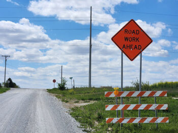 A sign alongside a rural highway warns of road work ahead.
