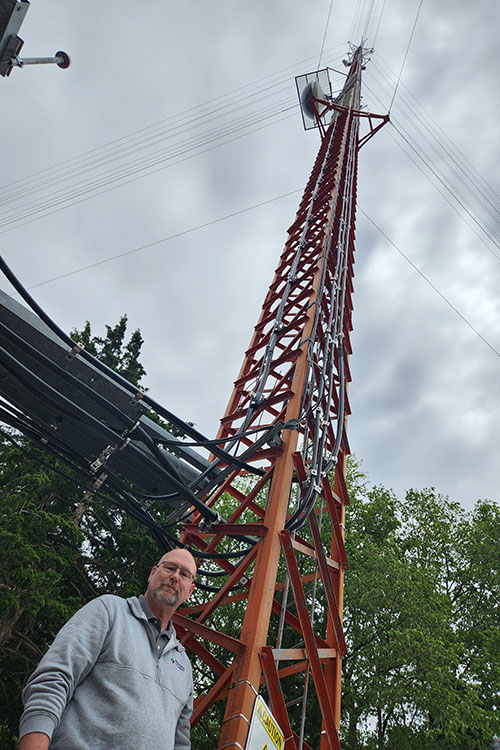 Telecommunications Team Lead Dan Weis stands near one of OPPD's orange radio towers.