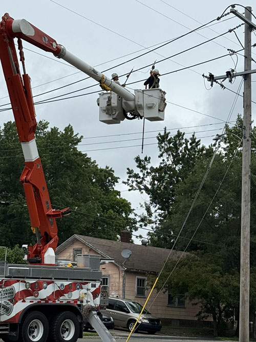 Two line technicians held aloft in buckets work to restore power.