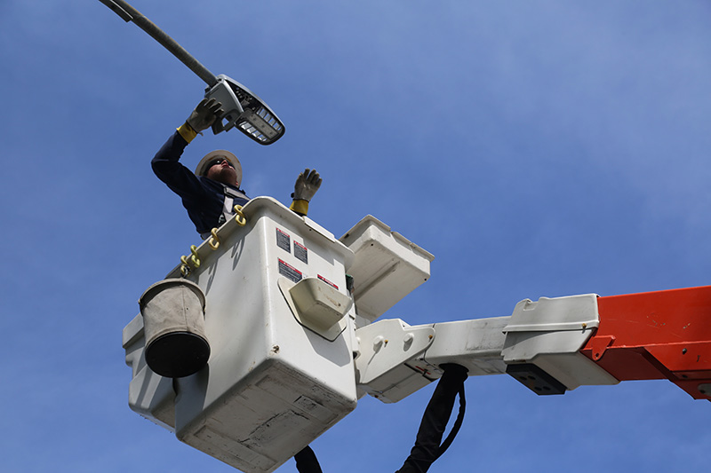 An OPPD employee standing in a bucket truck bucket works on a streetlight.