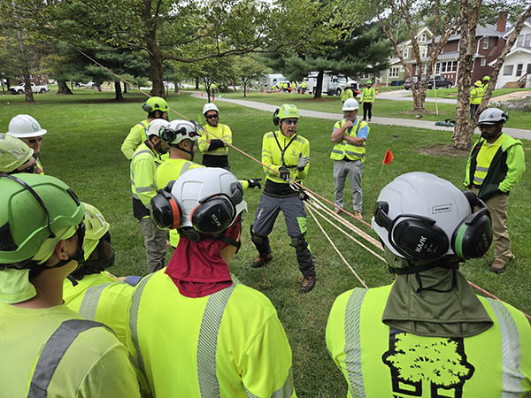 OPPD tree crew members watch a demonstration of how to use a set of pulleys to bring down a tree.